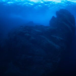 Dark underwater rock pinnacle silhouetted in deep blue water below the surface, Cabo Pearce (Socorro), Revillagigedo, Mexico