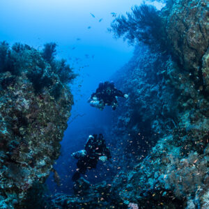 Two rebreather divers one above the other inside a reef canyon, Safaga, Red Sea, Egypt