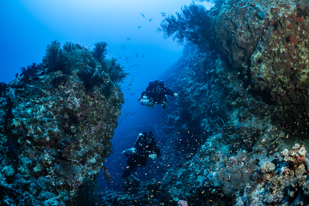Two rebreather divers one above the other inside a reef canyon, Safaga, Red Sea, Egypt