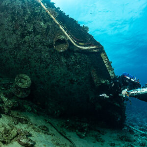 Rebreather diver beside the wreck hull with portholes and railings, Al Kahfain wreck, Red Sea, Egypt