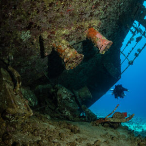 Rebreather diver below overturned deck fittings of the wreck, Al Kahfain wreck, Red Sea, Egypt