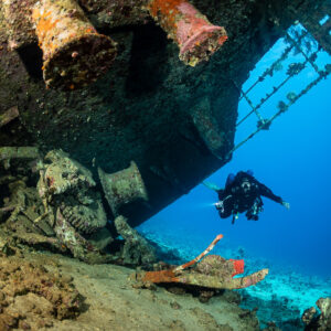 Rusty vents and railings of the inverted wreck above a diver, Al Kahfain wreck, Red Sea, Egypt
