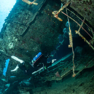 Diver under hanging railings of the inverted wreck, vertical view, Al Kahfain wreck, Red Sea, Egypt