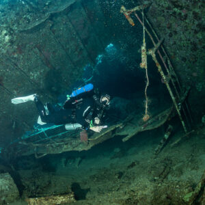 Rebreather diver inside the wreck with light from openings, Al Kahfain wreck, Red Sea, Egypt