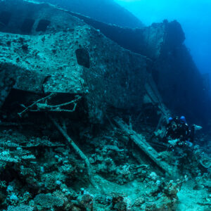 Diver dwarfed by the wreck side with rows of windows, Al Kahfain wreck, Red Sea, Egypt