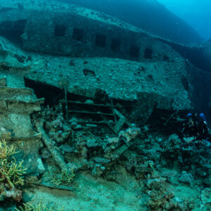Wreck side with corals growing on fallen debris and a diver, Al Kahfain wreck, Red Sea, Egypt