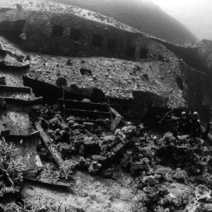 Black-and-white wreck side with corals on debris and diver, Al Kahfain wreck, Red Sea, Egypt