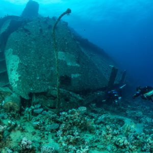 Divers beside a large wreck section with a hanging cable, Al Kahfain wreck, Red Sea, Egypt