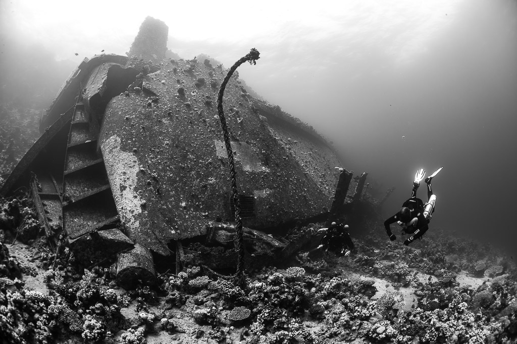 Black-and-white wreck section with hanging cable and diver, Al Kahfain wreck, Red Sea, Egypt
